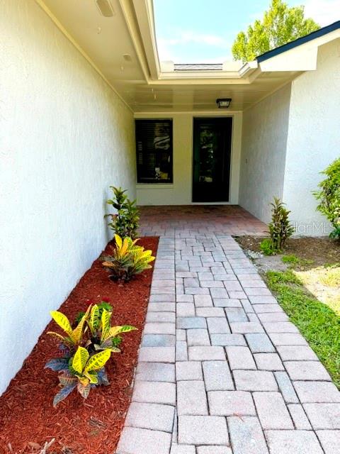 A paved walkway leads to the front entrance of a house with white stucco walls — 298 QUAIL COURT, CASSELBERRY, FL