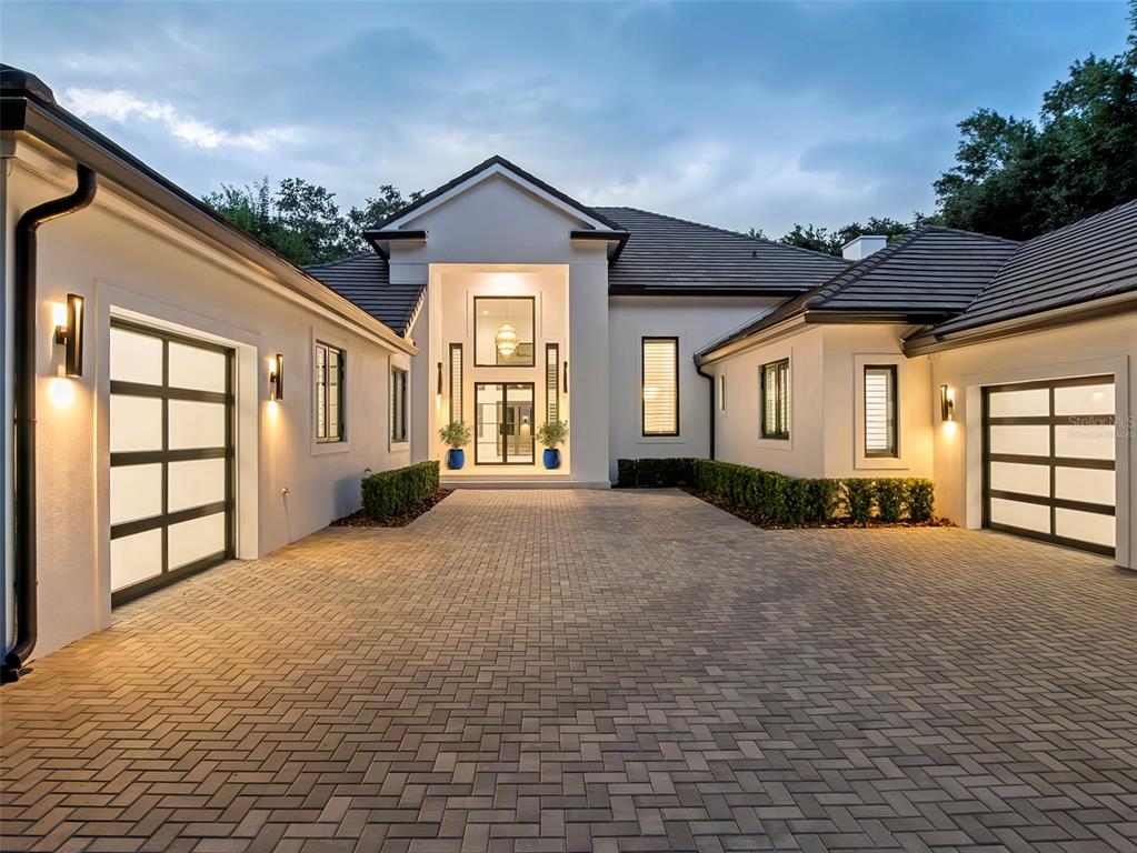 A modern house exterior features a paved driveway, two garage doors, and a central entryway — 5199 LATROBE DR, WINDERMERE, FL