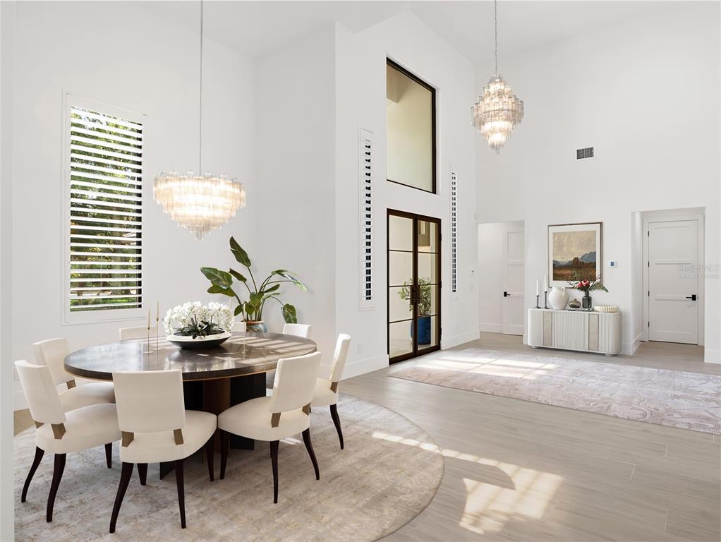 A bright dining room features a round table, white chairs, and two large crystal chandeliers — 5199 LATROBE DR, WINDERMERE, FL
