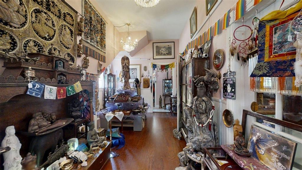 A room filled with spiritual decor, statues, tapestries, and prayer flags on hardwood floors — 805 E FORT KING STREET, OCALA, FL