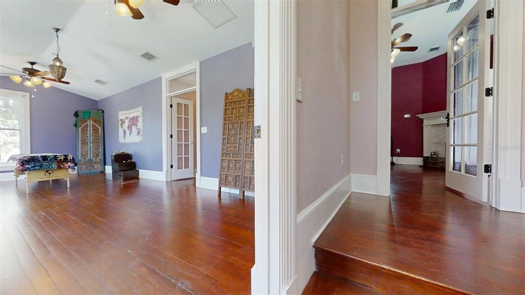 A room with purple walls and hardwood floors leads into another room with dark red walls — 805 E FORT KING STREET, OCALA, FL