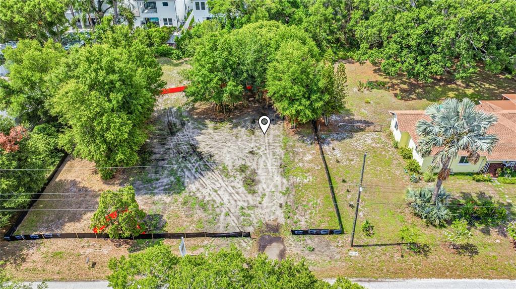 A vacant, fenced-in residential lot sits beside a paved road with trees in the background — 1008 W ADALEE STREET, TAMPA, FL