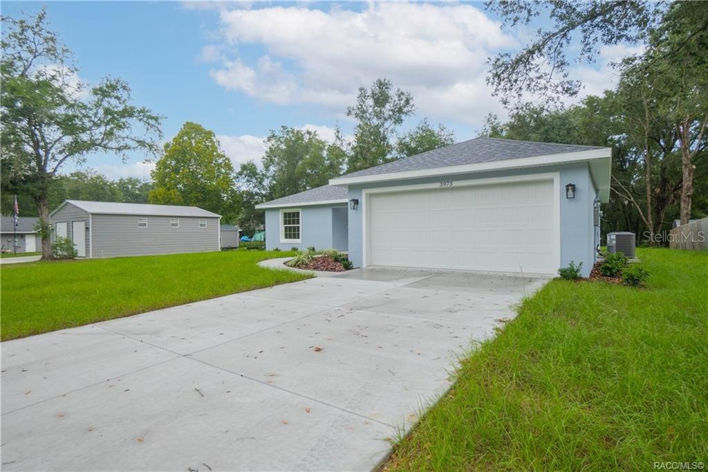 A light blue single-story house with a white garage door and a detached metal shed — 3973 E DANO STREET, INVERNESS, FL