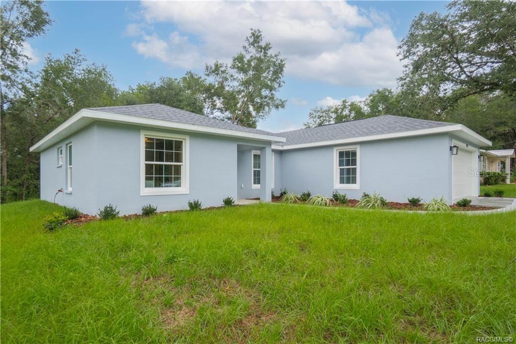 A light blue, single-story house with a hip roof and a front-facing garage — 3973 E DANO STREET, INVERNESS, FL
