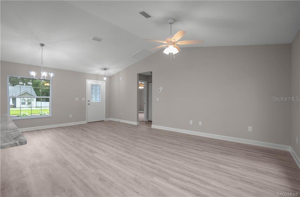 A living room with light wood-look flooring, a vaulted ceiling, and a ceiling fan — 3973 E DANO STREET, INVERNESS, FL