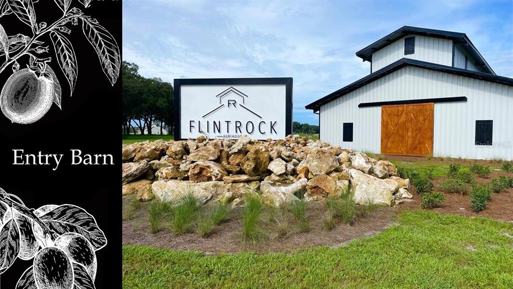 A white barn with wooden doors stands behind a large rock pile and sign — 5501 SW 125TH CIRCLE, ARCHER, FL
