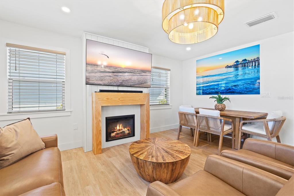 A living and dining area features a fireplace, a mounted television, and light wood flooring — 2226 ARLINGTON STREET, SARASOTA, FL