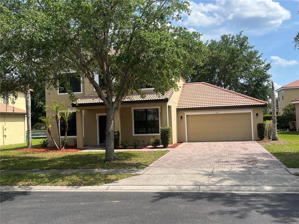A two-story suburban house with a tan exterior, tiled roof, and a two-car garage — 2821 SCENIC LANE, KISSIMMEE, FL