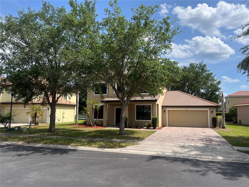 A two-story tan stucco house with a tile roof, a garage, and a front tree — 2821 SCENIC LANE, KISSIMMEE, FL