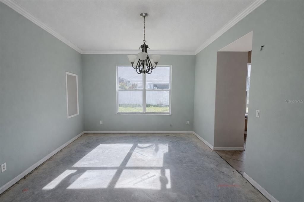 An empty dining room with light blue walls, a chandelier, and an unfinished concrete floor — 3734 MOON DANCER PLACE, ST CLOUD, FL