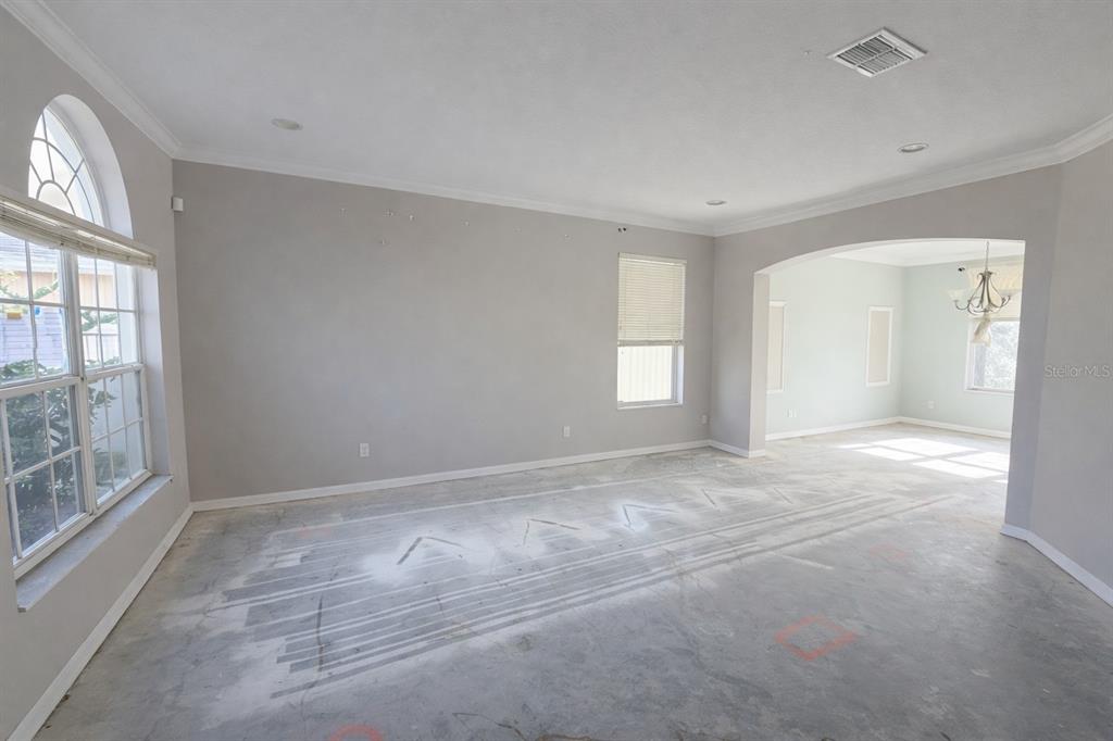 An empty room with light gray walls, arched windows, and an exposed concrete subfloor — 3734 MOON DANCER PLACE, ST CLOUD, FL