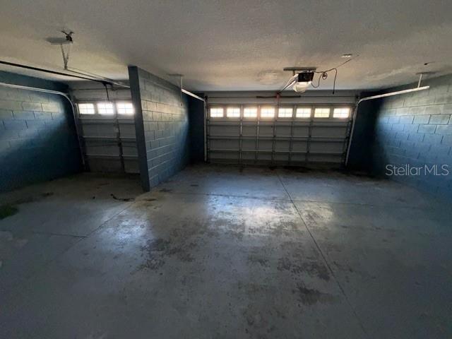 An empty two-car garage features gray painted concrete block walls and a concrete floor — 3734 MOON DANCER PLACE, ST CLOUD, FL