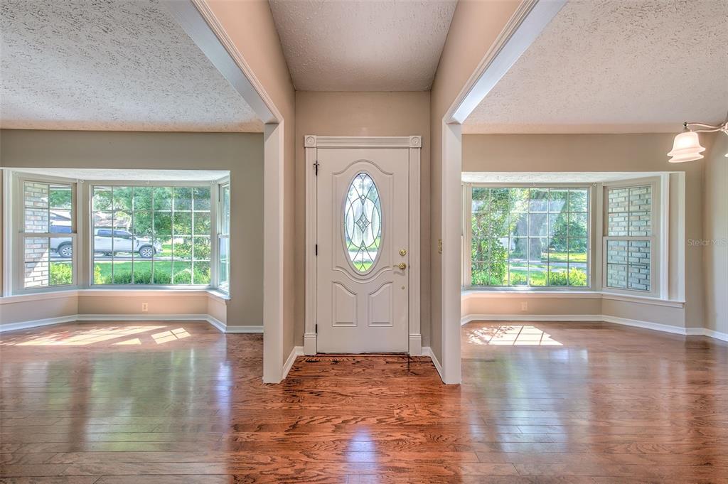 An entryway with a dark wood front door, hardwood floors, and two adjacent living areas — 2102 WHITLOCK PLACE, DOVER, FL
