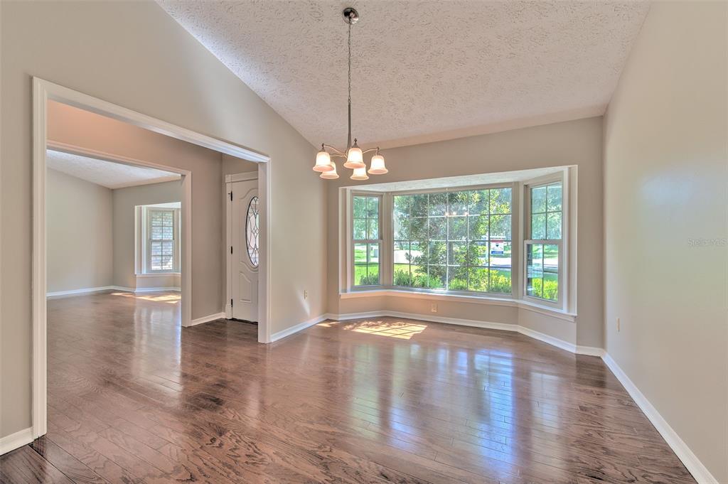 A dining room with hardwood floors, a bay window, wallpaper, and a hanging light fixture — 2102 WHITLOCK PLACE, DOVER, FL