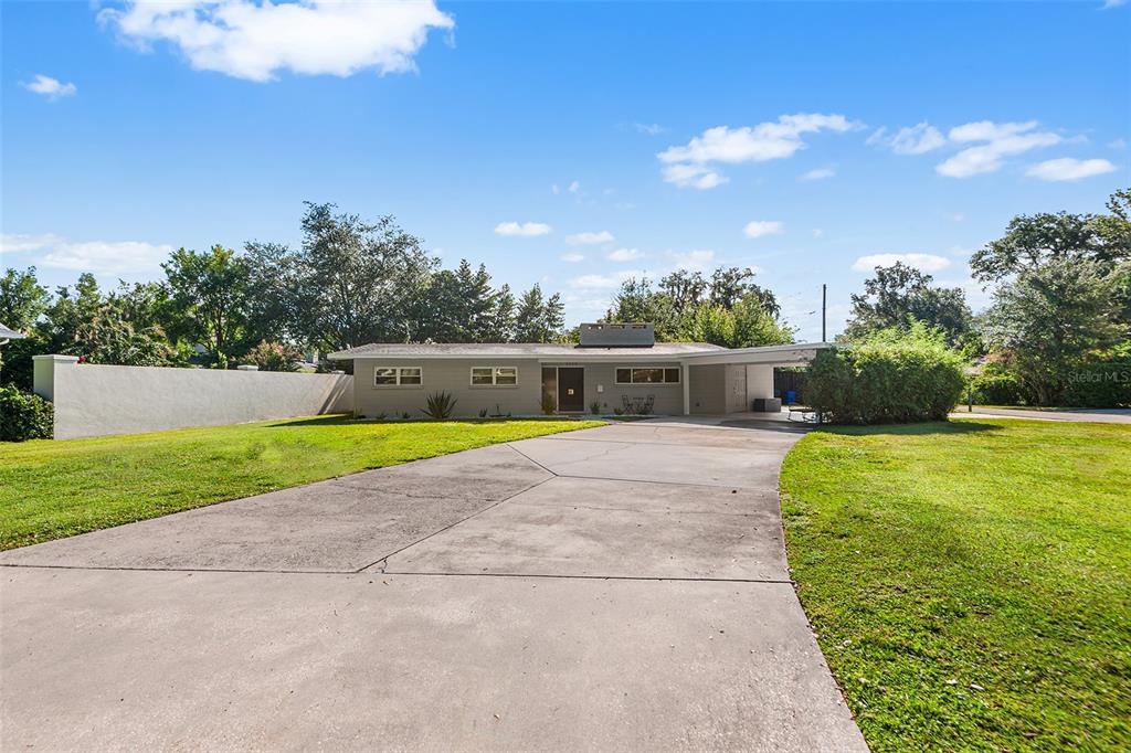 A single-story house with a concrete driveway, carport, and a large front lawn — 2624 EASTON TERRACE, LAKELAND, FL