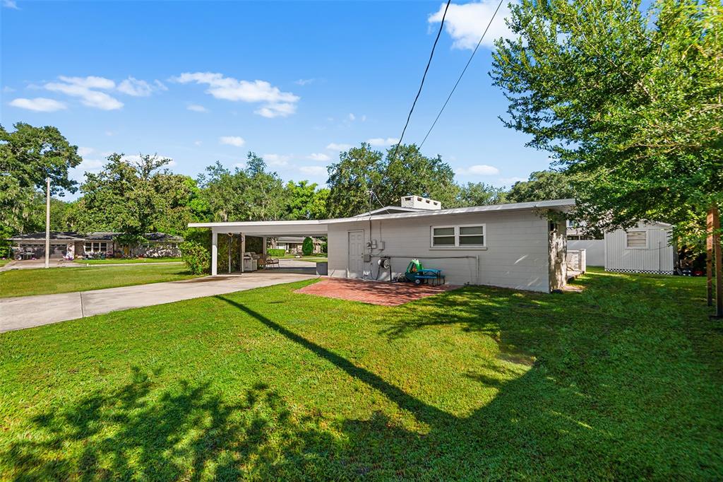 A gray single-story house with a carport, brick patio, and a large grassy yard — 2624 EASTON TERRACE, LAKELAND, FL