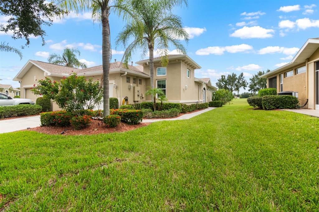 A tan stucco house with a palm tree and landscaped garden in the front yard — 1160 JAMESON GREENS DRIVE, SUN CITY CENTER, FL