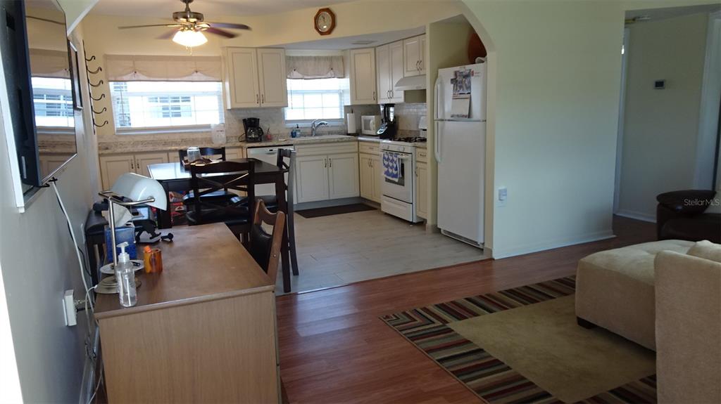 An open-concept kitchen with white cabinets and a dining area flows into a living space — 7729 39TH TERRACE N, ST PETERSBURG, FL
