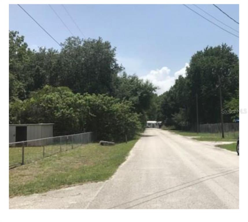 A gravel road leads toward a small house surrounded by dense trees and a fence — 14969 OGDEN LOOP, ODESSA, FL