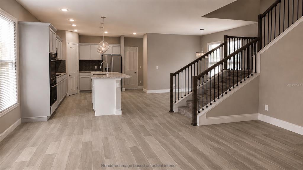 This rendering shows a kitchen with white cabinets and an island next to a staircase — 10301 AUSTRINA OAK LOOP, WINTER GARDEN, FL