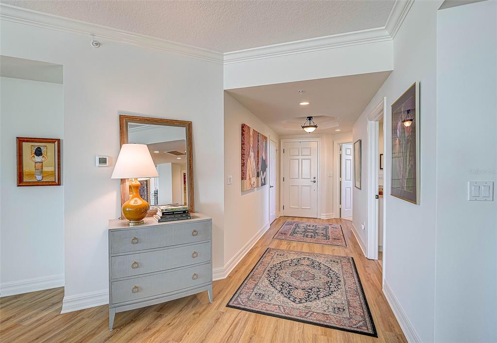 A hallway features light wood flooring, two area rugs, a gray dresser, and wall art — 3603 N POINT ROAD UNIT 602, OSPREY, FL