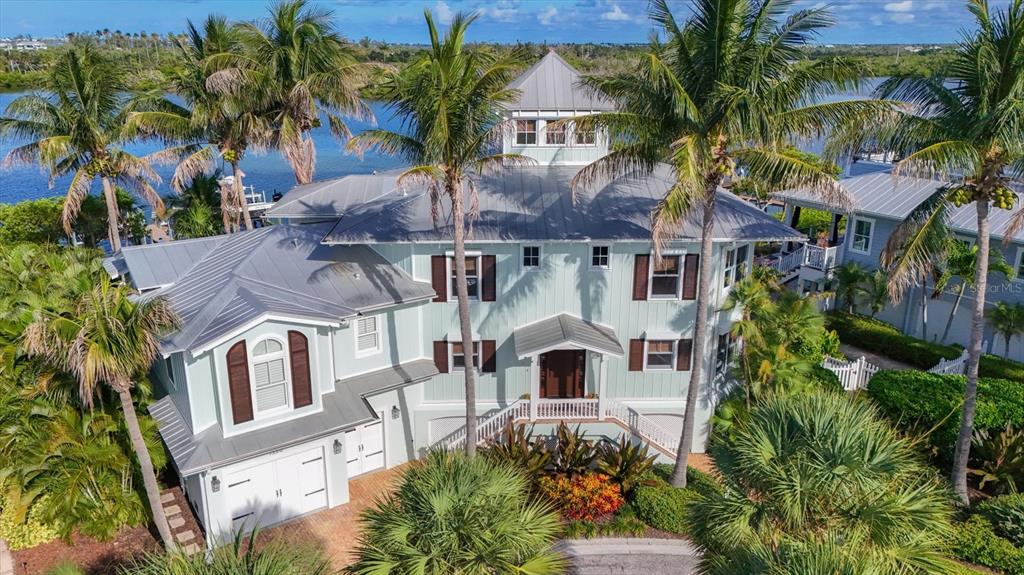 A light blue three-story coastal home with a metal roof surrounded by palm trees — 13310 ANGLERS WAY, PLACIDA, FL