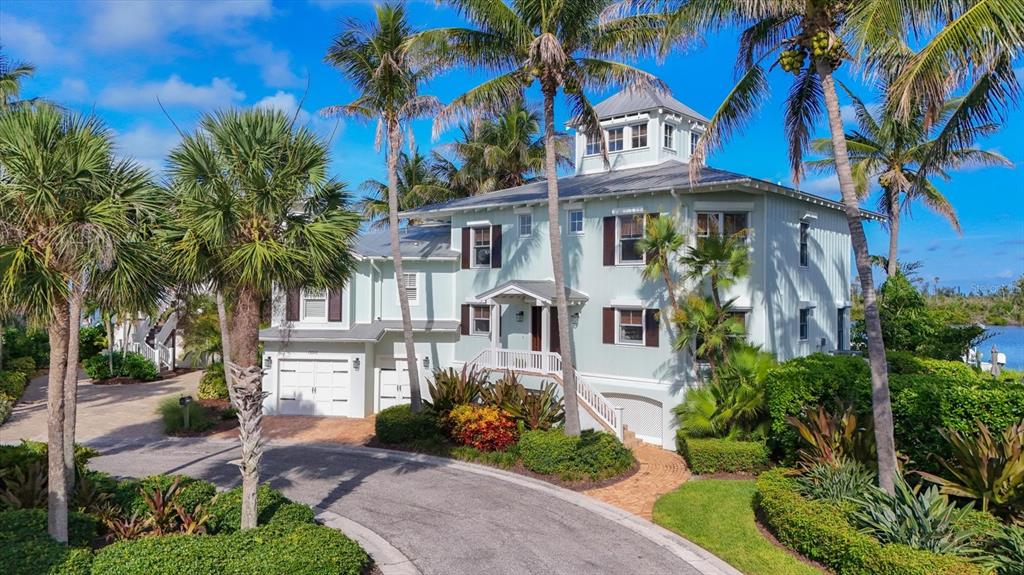A light green three-story coastal house with a metal roof and palm trees — 13310 ANGLERS WAY, PLACIDA, FL