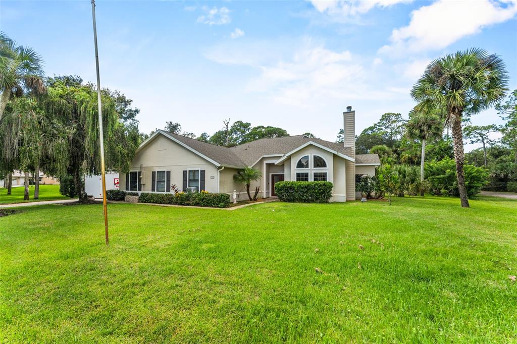 A single-story house with a beige exterior, a chimney, and a large front lawn — 5560 BOB WHITE TRAIL, MIMS, FL