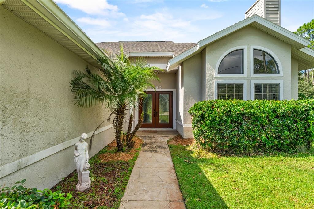 A stone walkway leads to the front entrance of a house with a palm tree — 5560 BOB WHITE TRAIL, MIMS, FL