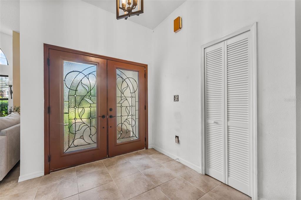 An entryway features double wood-framed glass doors, tile flooring, and a white louvered closet door — 5560 BOB WHITE TRAIL, MIMS, FL