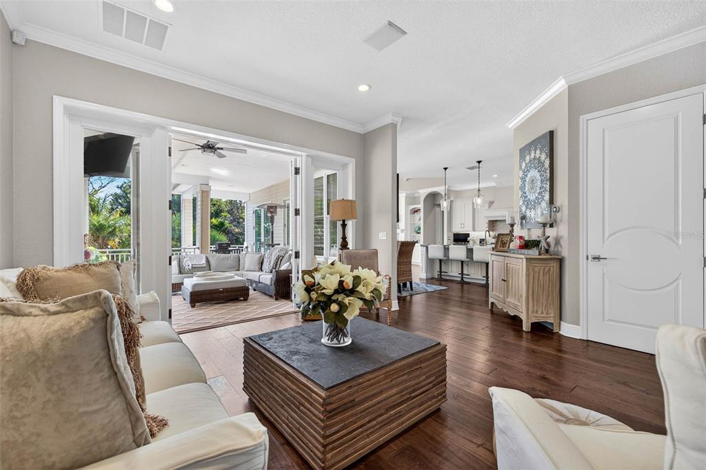 A living room with hardwood floors opens to a covered patio through sliding glass doors — 1581 ALEXANDER ROAD, BELLEAIR, FL