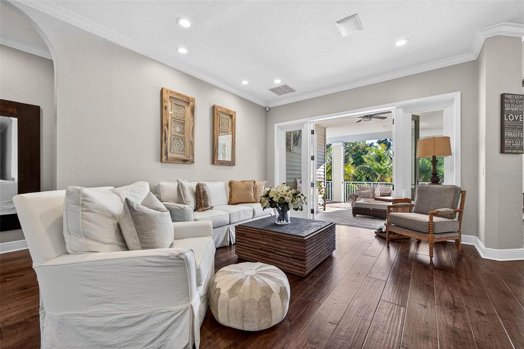 A living room features white sofas, a wooden coffee table, and sliding doors to a patio — 1581 ALEXANDER ROAD, BELLEAIR, FL