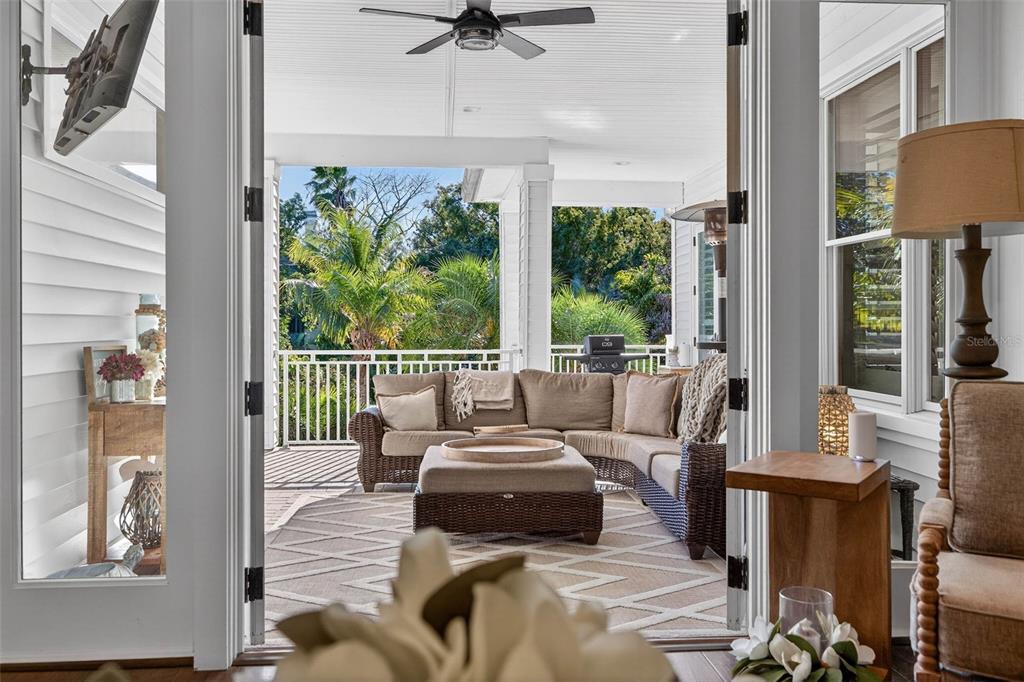 A view from an interior room looking out onto a covered patio with wicker furniture — 1581 ALEXANDER ROAD, BELLEAIR, FL
