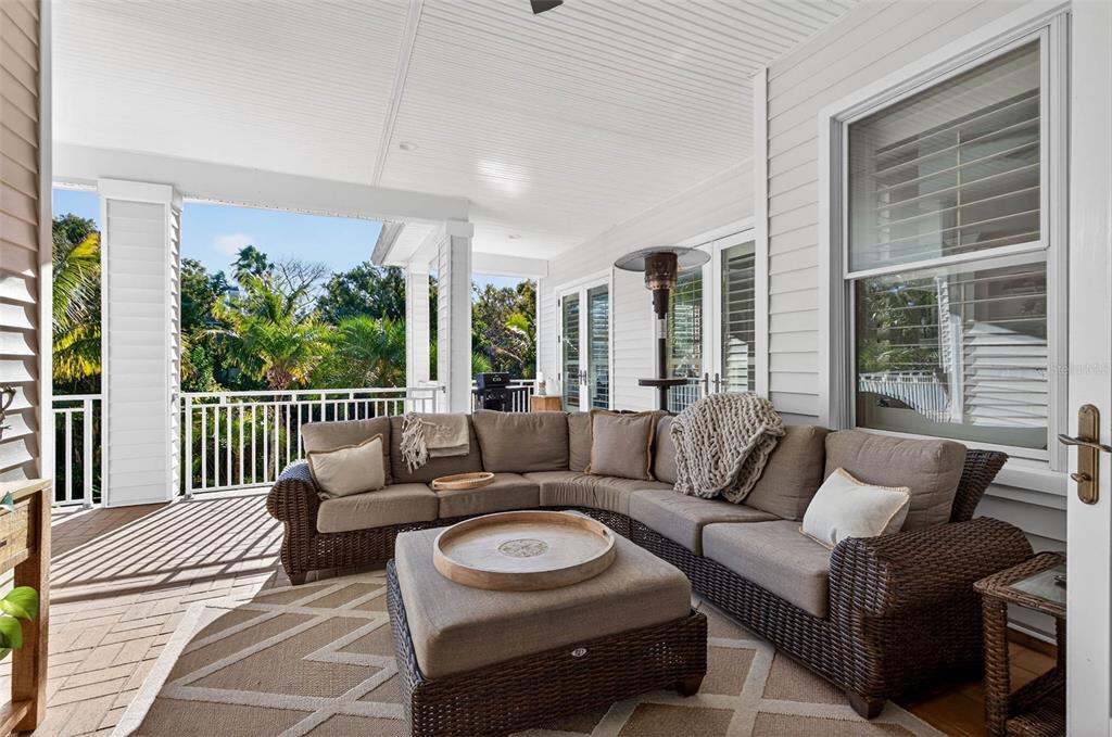 A covered outdoor patio features a wicker sectional sofa, a central ottoman, and a ceiling fan — 1581 ALEXANDER ROAD, BELLEAIR, FL