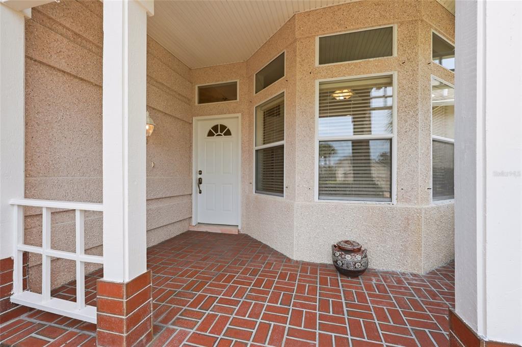 A covered front porch features a red brick floor, stucco walls, and a white door — 272 SEA WOODS DRIVE N, ST AUGUSTINE, FL