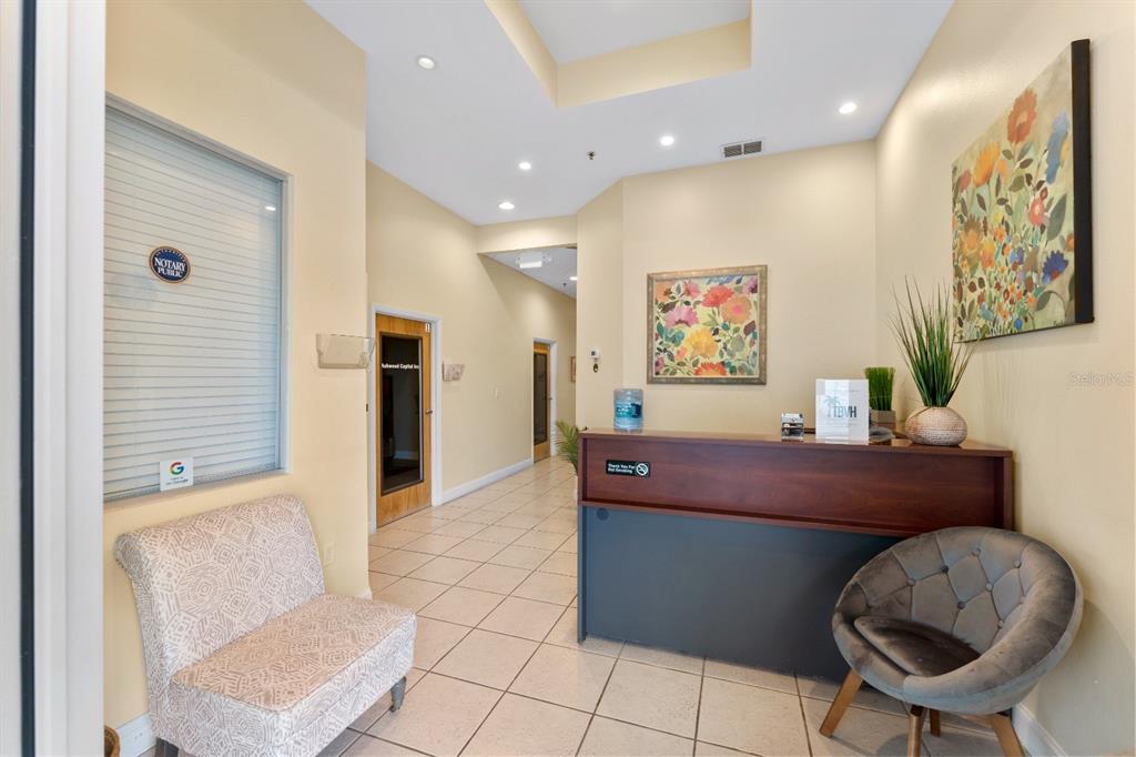 A reception area features a dark wood desk, tile flooring, and two chairs — 8810 COMMODITY CIR UNIT 36, ORLANDO, FL