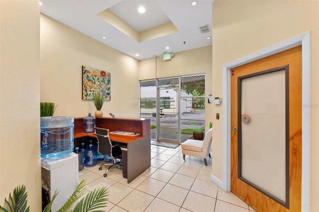 A reception area features a desk, tile flooring, a water cooler, and a glass entrance door — 8810 COMMODITY CIR UNIT 36, ORLANDO, FL
