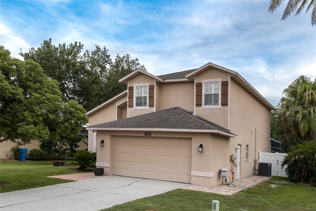 A two-story tan stucco house with a two-car garage and brown shutters — 4906 AUGUSTA AVENUE, OLDSMAR, FL