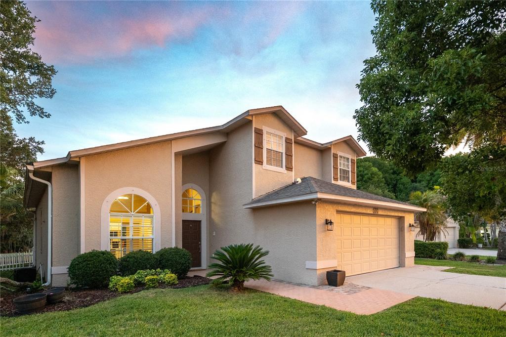 A two-story suburban house with a tan stucco exterior, a two-car garage, and arched windows — 4906 AUGUSTA AVENUE, OLDSMAR, FL