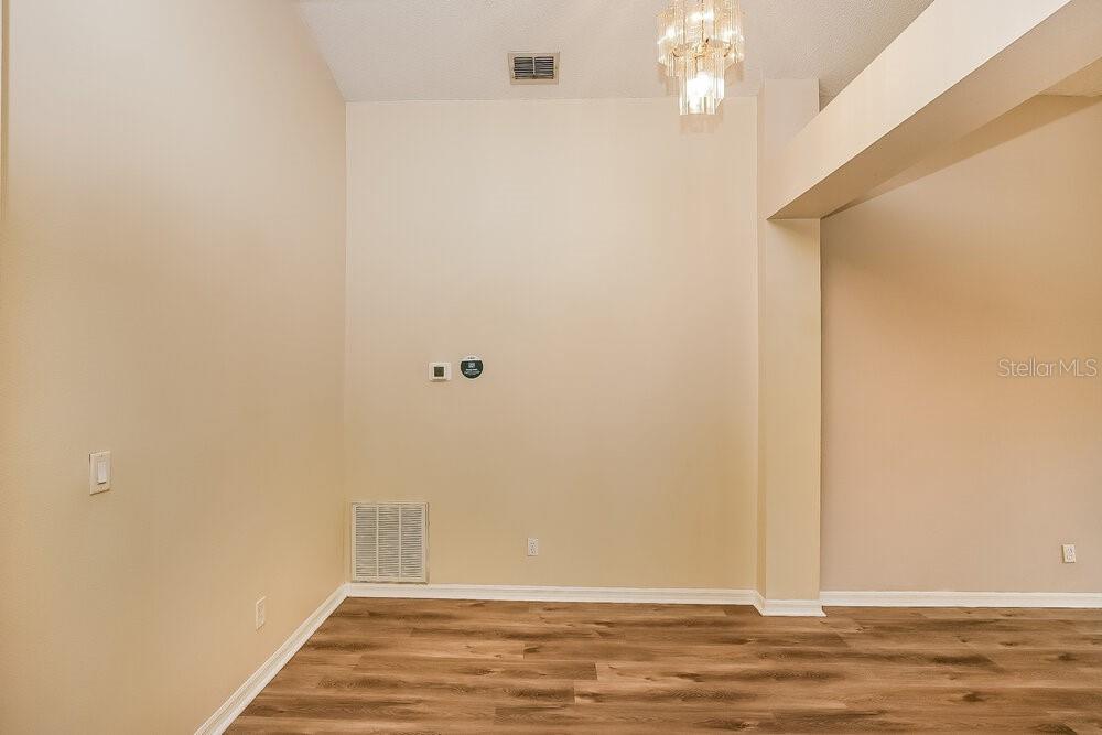 An empty room with beige walls, wood-look flooring, and a crystal chandelier — 1289 HIMALAYAN COURT, APOPKA, FL