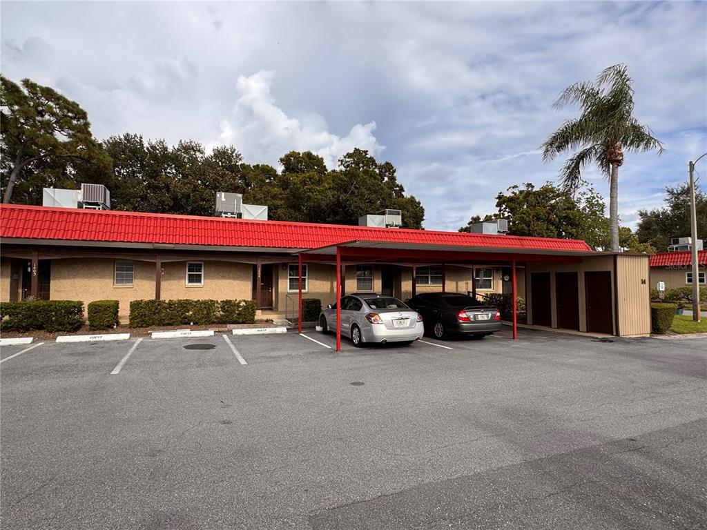 A single-story apartment building with a red metal roof and a covered parking area — 601 N HERCULES AVENUE UNIT 1404, CLEARWATER, FL