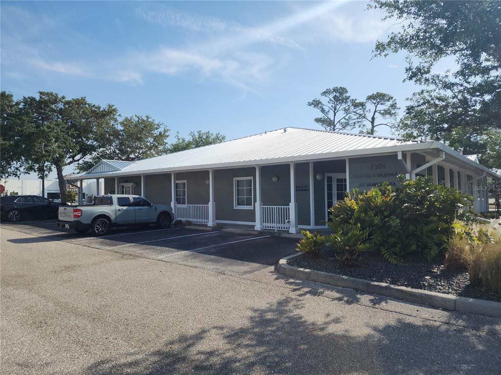 A single-story commercial building with a white metal roof and gray siding — 17801 MURDOCK CIRCLE UNIT A, PORT CHARLOTTE, FL