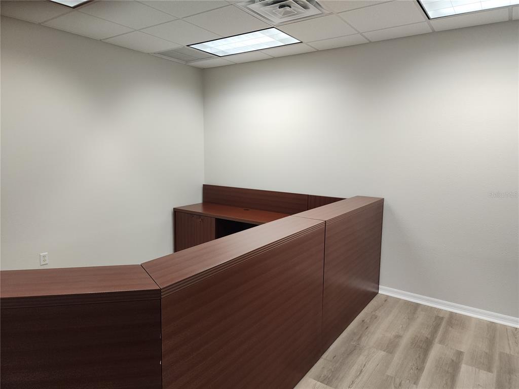 An office space features a dark wood reception desk, light grey walls, and wood-look flooring — 17801 MURDOCK CIRCLE UNIT A, PORT CHARLOTTE, FL