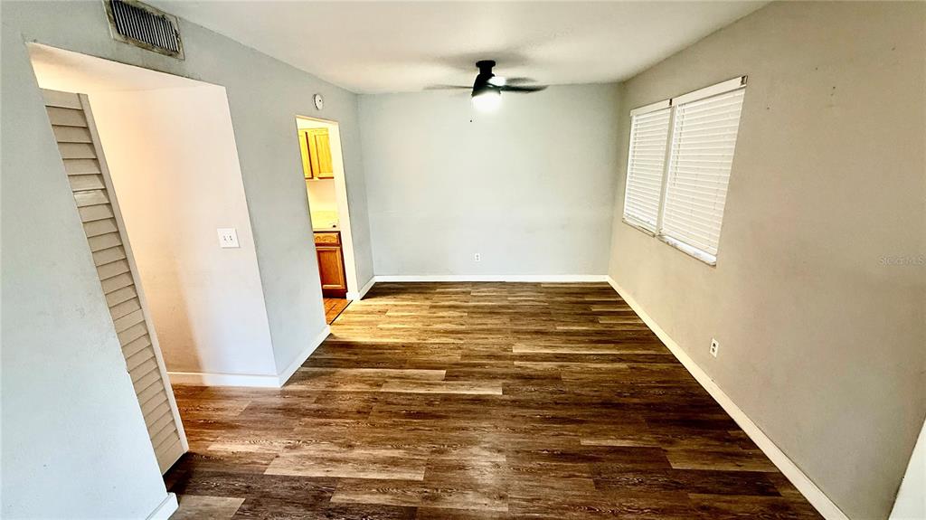 An empty living room features wood-look flooring, gray walls, a ceiling fan, and sliding glass doors — 6519 W NEWBERRY ROAD UNIT 812, GAINESVILLE, FL