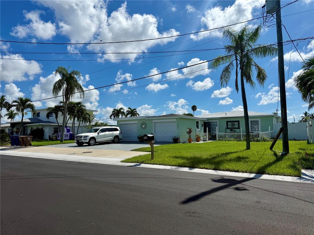 A light green single-story house with a two-car garage and a white picket fence — 722 PRUITT DRIVE, MADEIRA BEACH, FL
