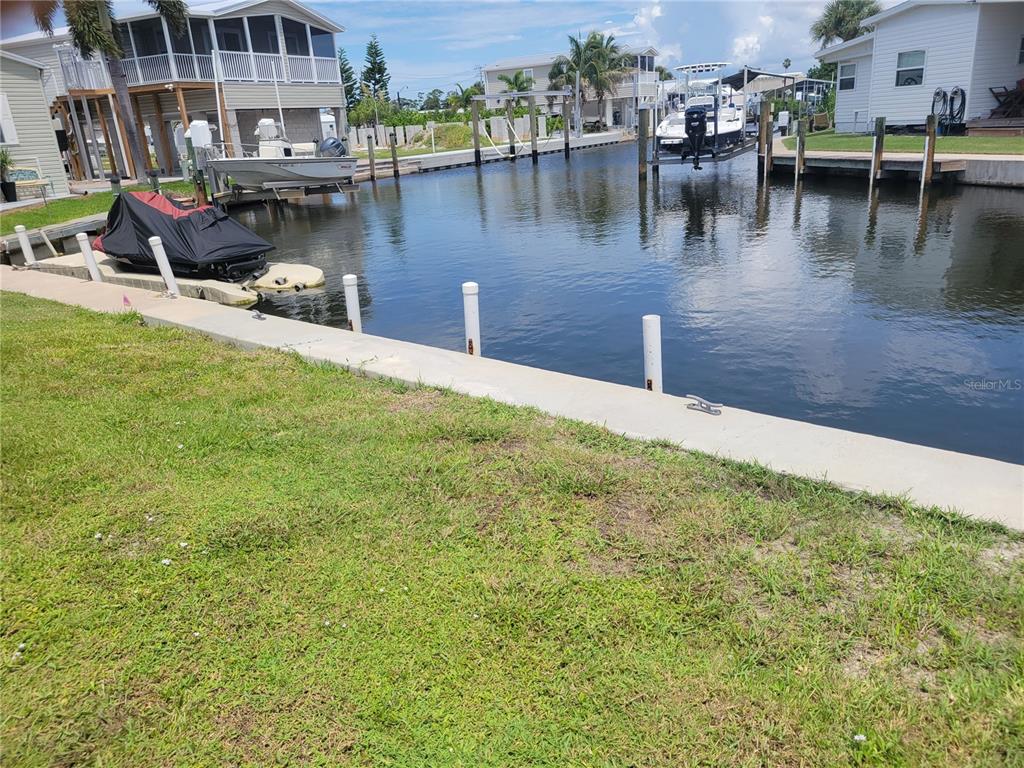 A canal view showing a concrete seawall, a jet ski, and two boats on lifts — 138 BAYOU DRIVE, VENICE, FL
