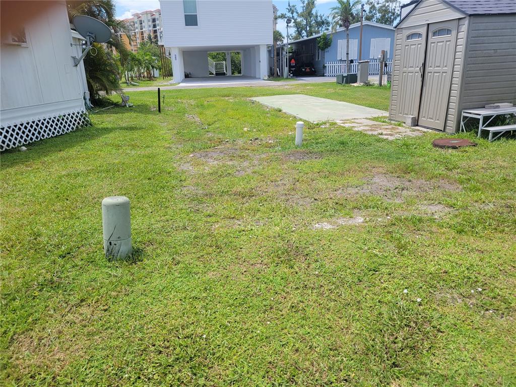 A grassy lot features a utility pedestal, a concrete pad, and a storage shed — 138 BAYOU DRIVE, VENICE, FL