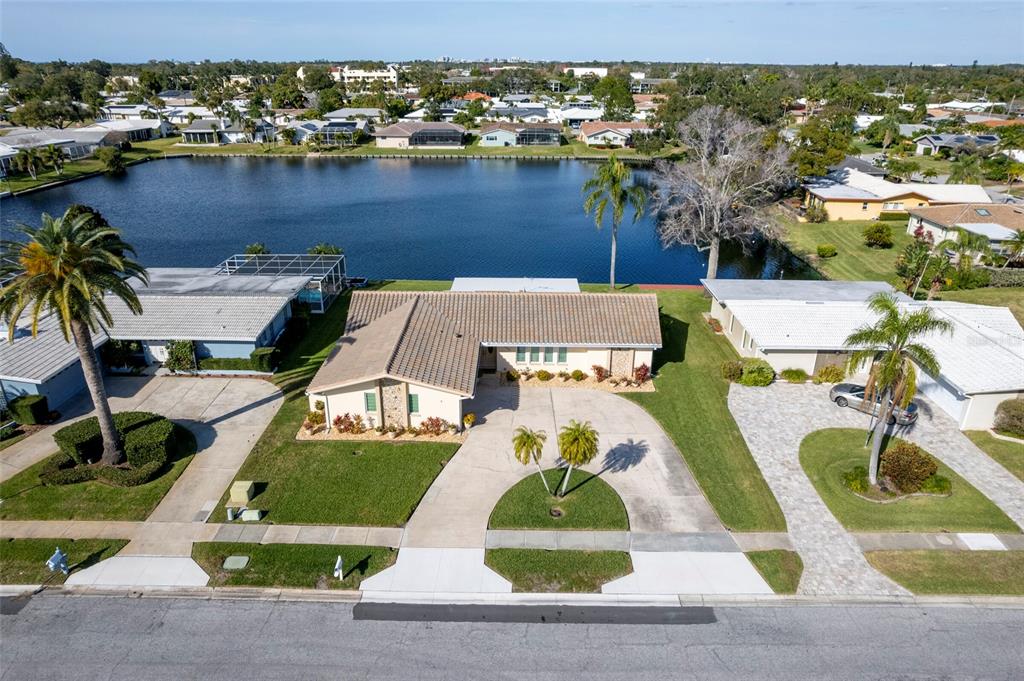An aerial view shows a single-story house with a tiled roof, driveway, and waterfront backyard — 13797 PINECREST DRIVE, LARGO, FL