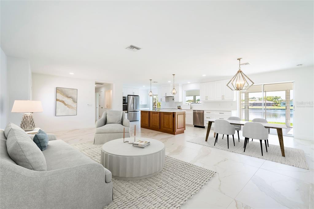 An open-concept living and dining area features white tile floors, a kitchen island, and water views — 13797 PINECREST DRIVE, LARGO, FL