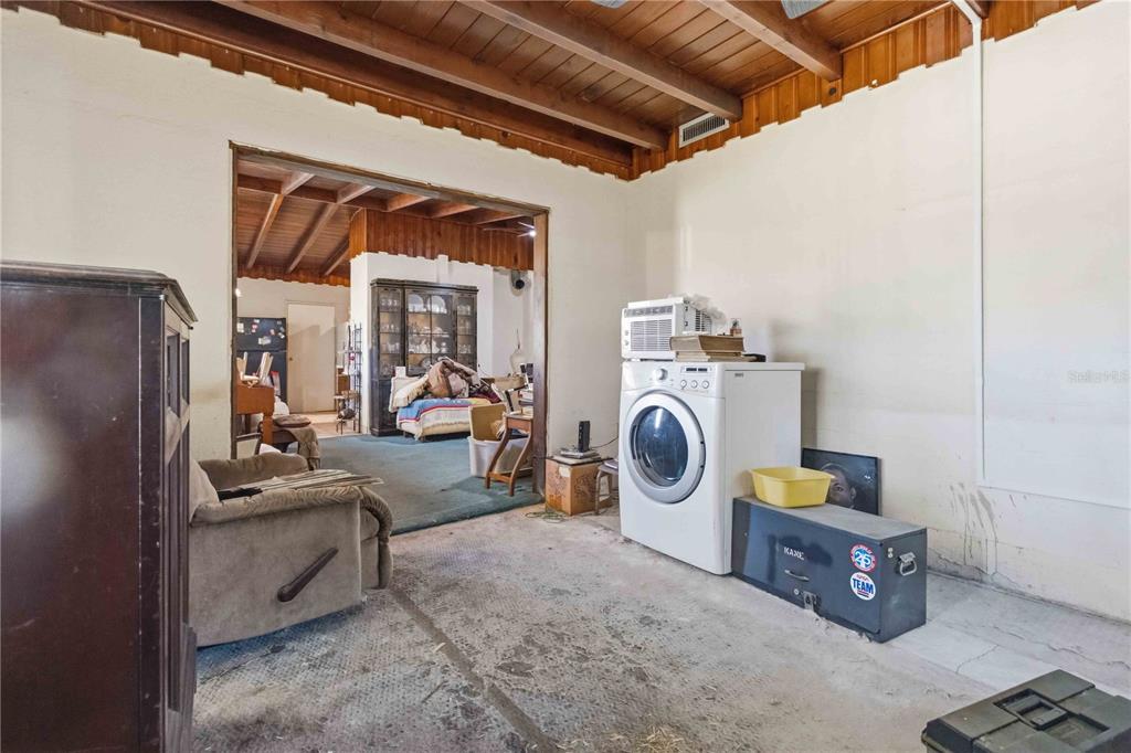A utility room with a concrete floor, exposed wood ceiling, and a white clothes dryer — 214 BLAKE AVENUE, COCOA, FL
